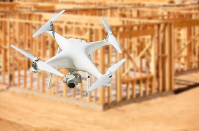 Unmanned Aircraft System (UAV) Quadcopter Drone In The Air Over Construction Site.