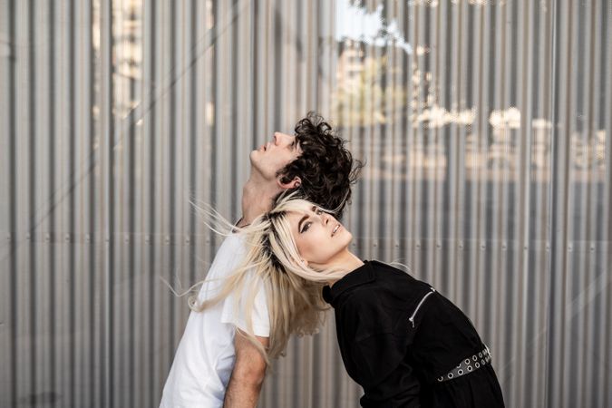 Loving man and woman supporting each other while standing back to back