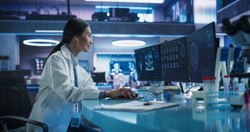 Cancer Research Center Medical Laboratory: Asian Female Neuroscientist Using Desktop Computer To Analyze CT Scans Of Human Brain.