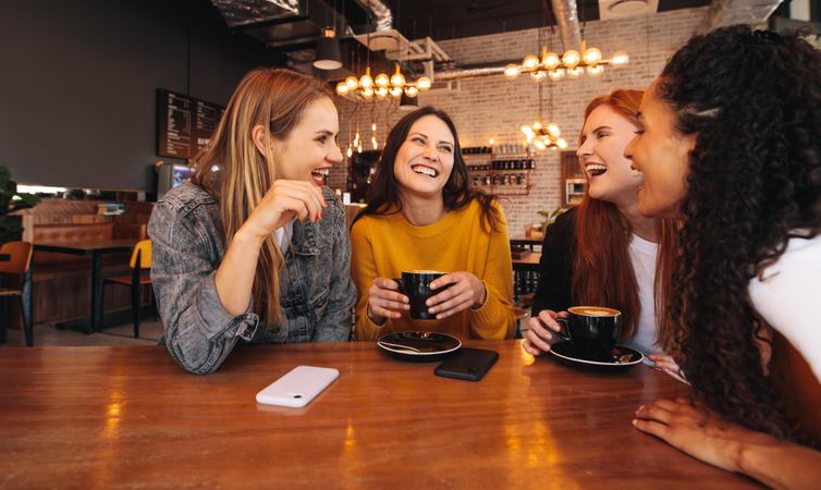 Four female friends meeting in a coffee shop on a weekend