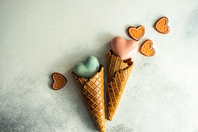Two ceramic hearts in waffle cones on grey background with various Valentine ornaments