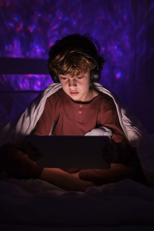 Focused boy browsing tablet in darkness at home