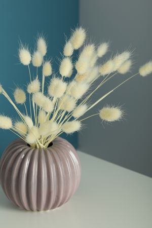 Round and ridged vase in blue and grey room filled with dried flowers, vertical