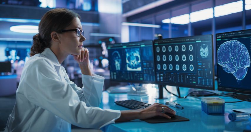 Hospital Research Laboratory: Female Medical Scientist Using Computer with Brain Scan MRI Images.