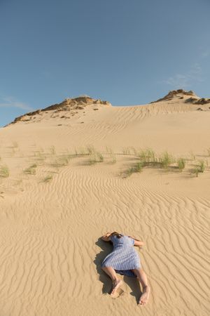 Young woman lying down on sand dune