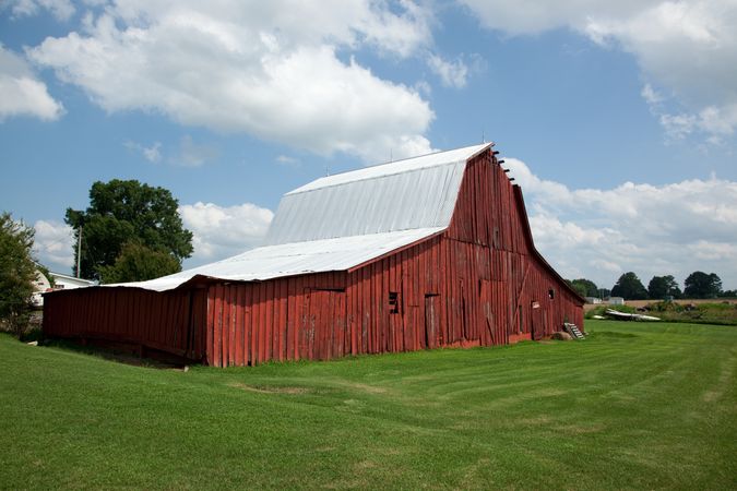 Large red wooden barn with fresh cut grass lawn in rural Alabama