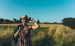 Female farmer with hat looking at her wheat crop.