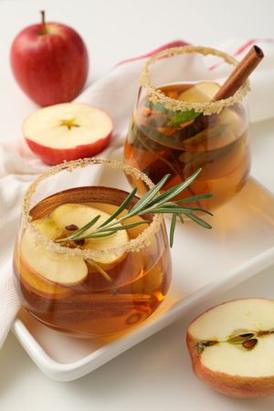 Glasses with apple cider and apples on towel, close up