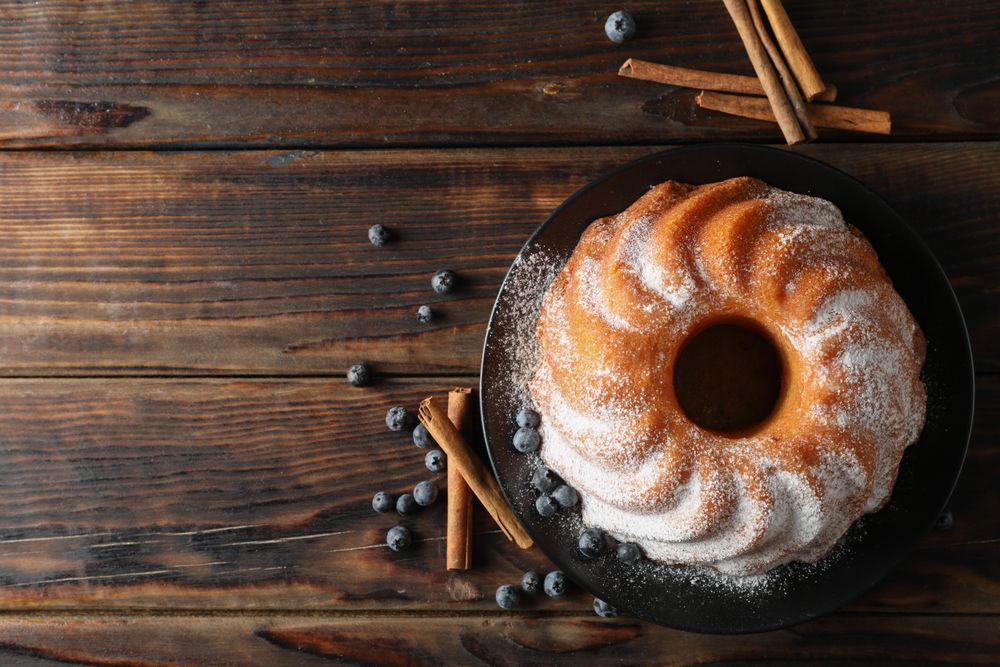 Cake with powder sugar and blueberry on wooden background, top view