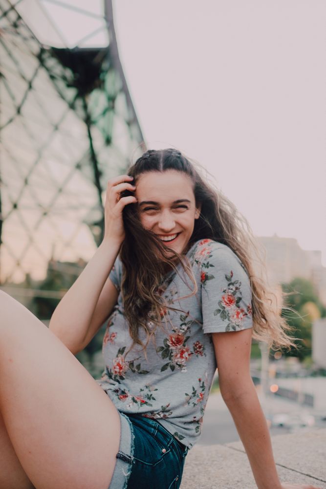 Smiling modern woman sitting on parapet