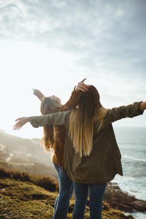 Happy female travelers enjoying freedom at seaside