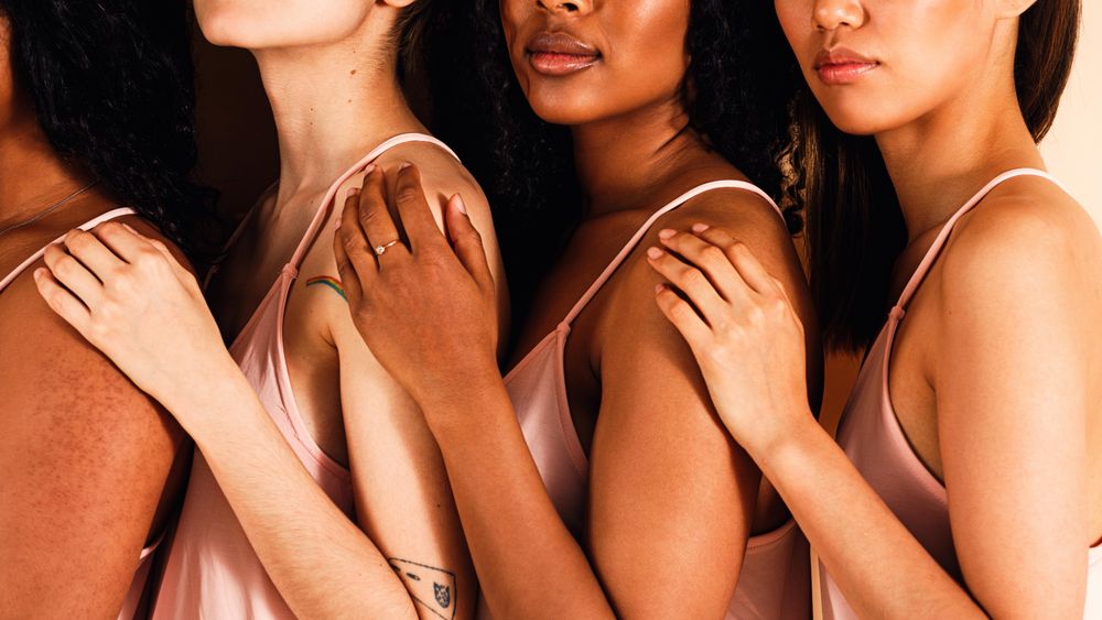 Group of diverse woman in a line holding each others shoulders