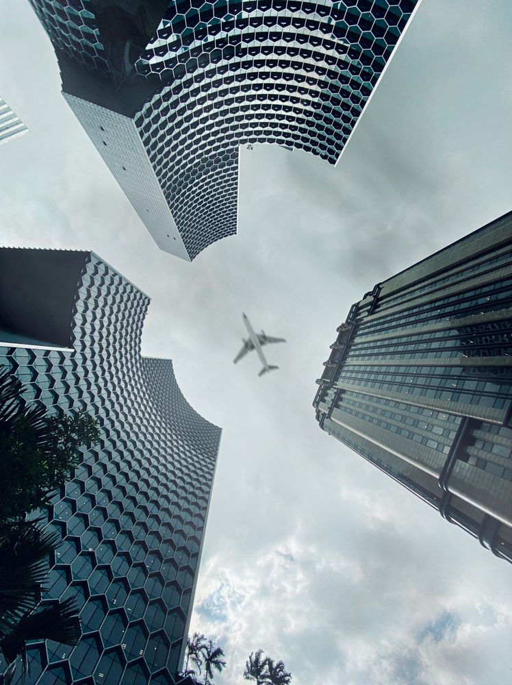 Low angle view of airplane above skyscrapers in Bugis, Singapore