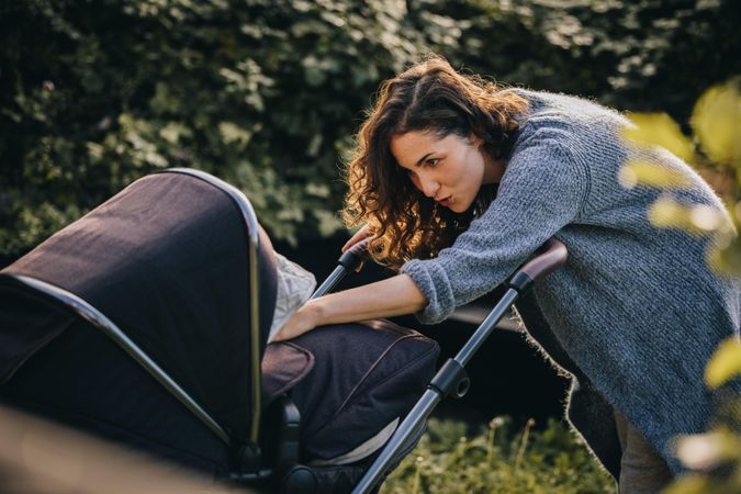 New mother checking on her newborn baby inside stroller