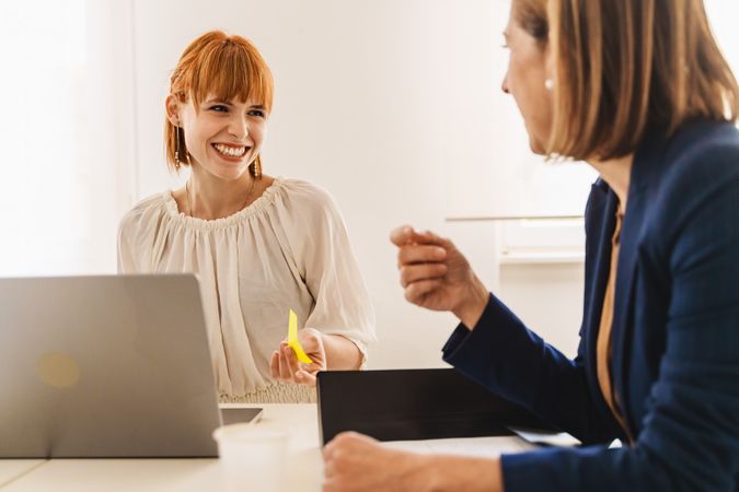 Smiling redhead woman with a nose piercing discusses work with her colleague