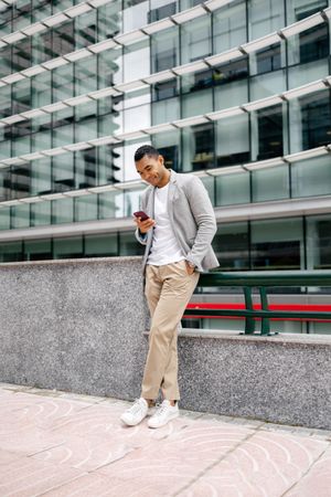 Man using smartphone leaning against wall