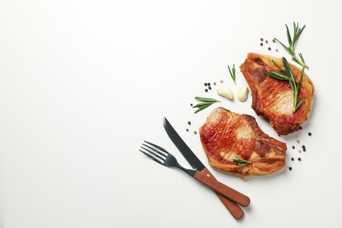 Fried steaks with spices on blank background, top view