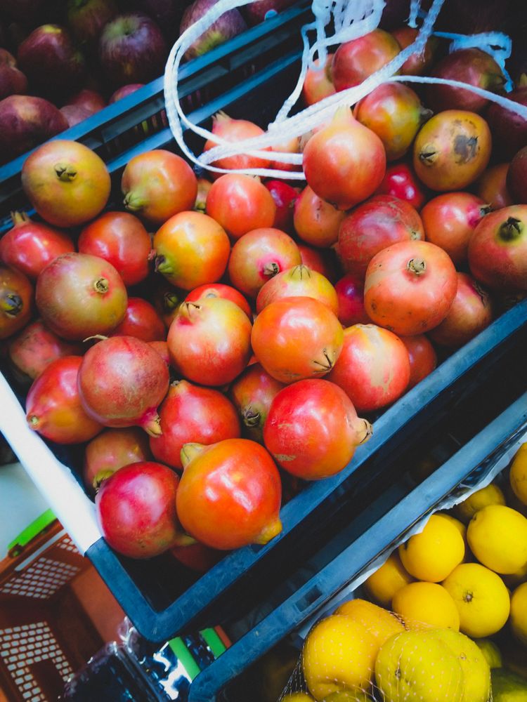 Red pomegranates and lemon in plastic crates