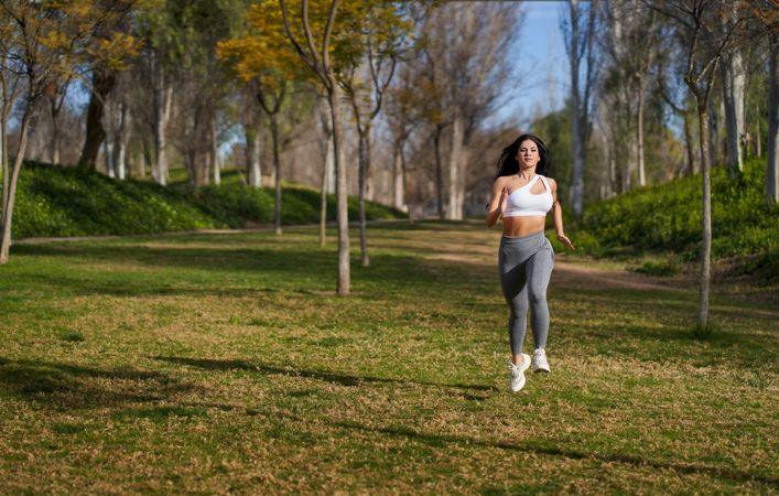an athletic woman running in a park with her hair down