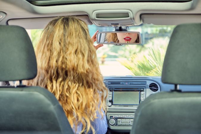 Woman applying lipstick in car