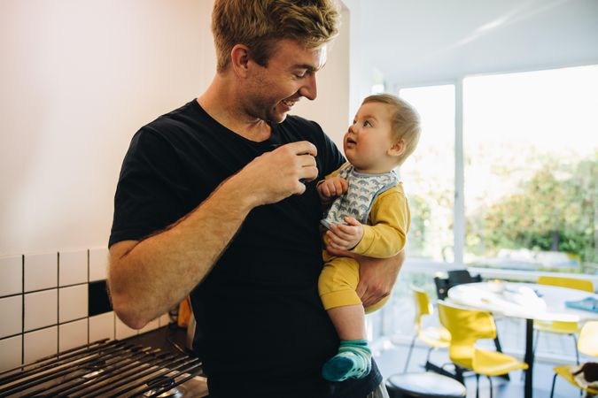 Curious baby boy looking up at his father as he holds coffee cup