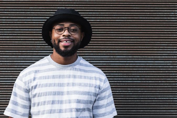Smiling Black hipster man in hat looking at camera