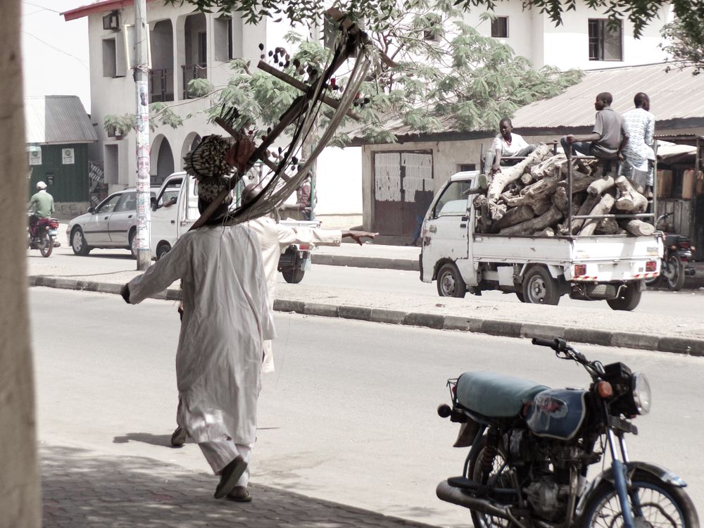Back view of African man holding a traditional instrument walking on sidewalk