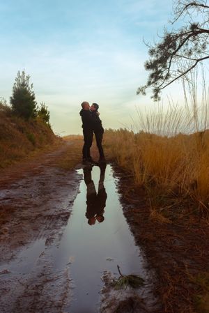 Men hugging and kissing near water puddle