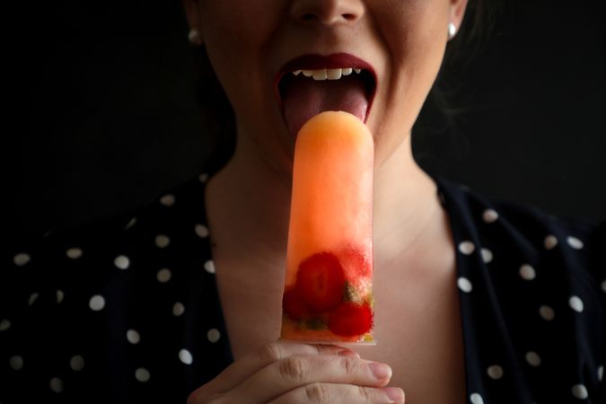 Woman eating fruit popsicle with berries