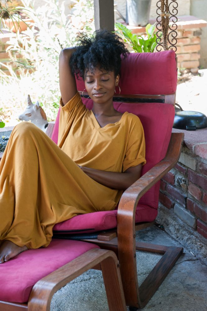 Woman sitting in chair on outside patio smiling with eyes closed