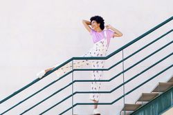 Woman on stairs with leg up on green handrail and arms on hair