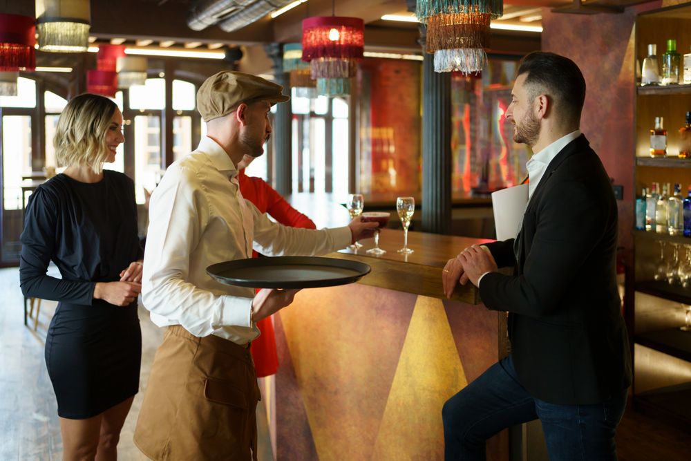 Bartender putting down red cocktail for guest