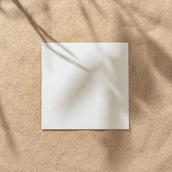 Sand with palm leaf shadows and central square