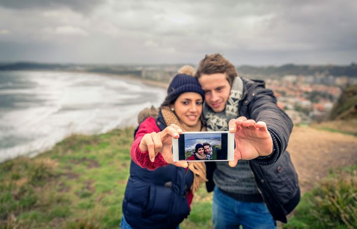 Couple taking selfie on top of cliff by the sea