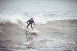 Surfer in wetsuit riding on wave on surfboard in ocean