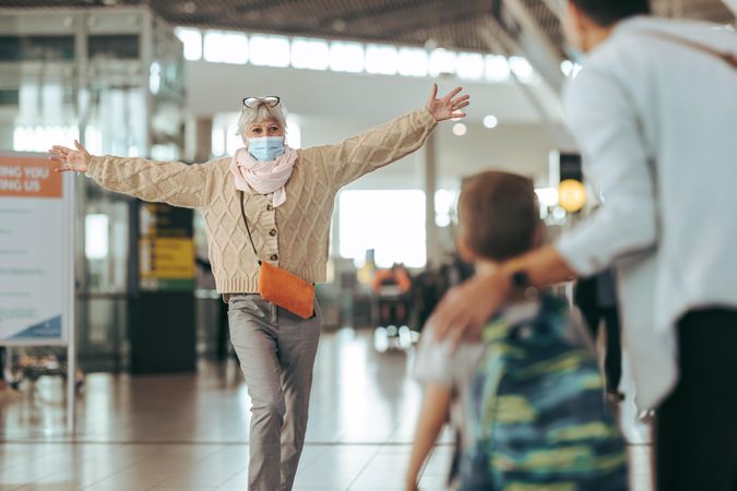 Woman with open arms at airport receiving her family arriving at airport