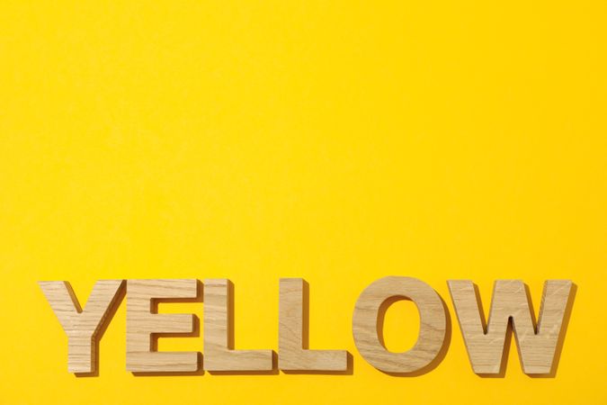 Word Yellow laid out in wooden letters on color background