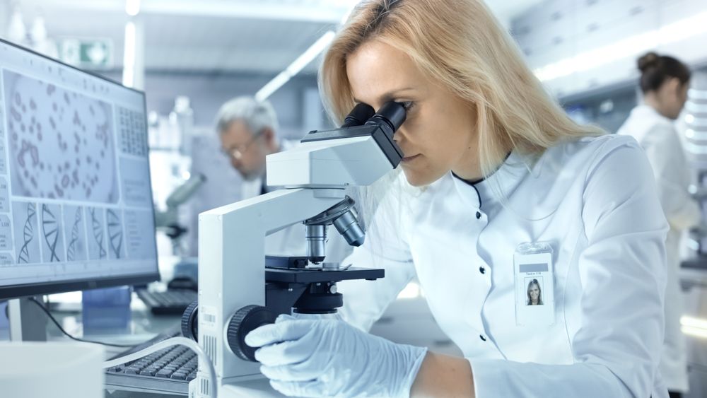 Female Research Scientist Looks at Biological Samples Under Microscope.