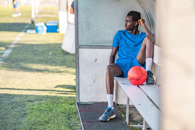 Black football player resting on bench