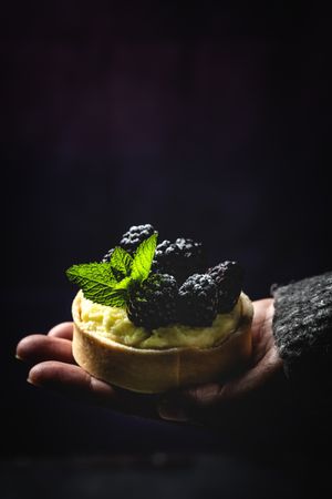 Hand holding a blackberry tartlet