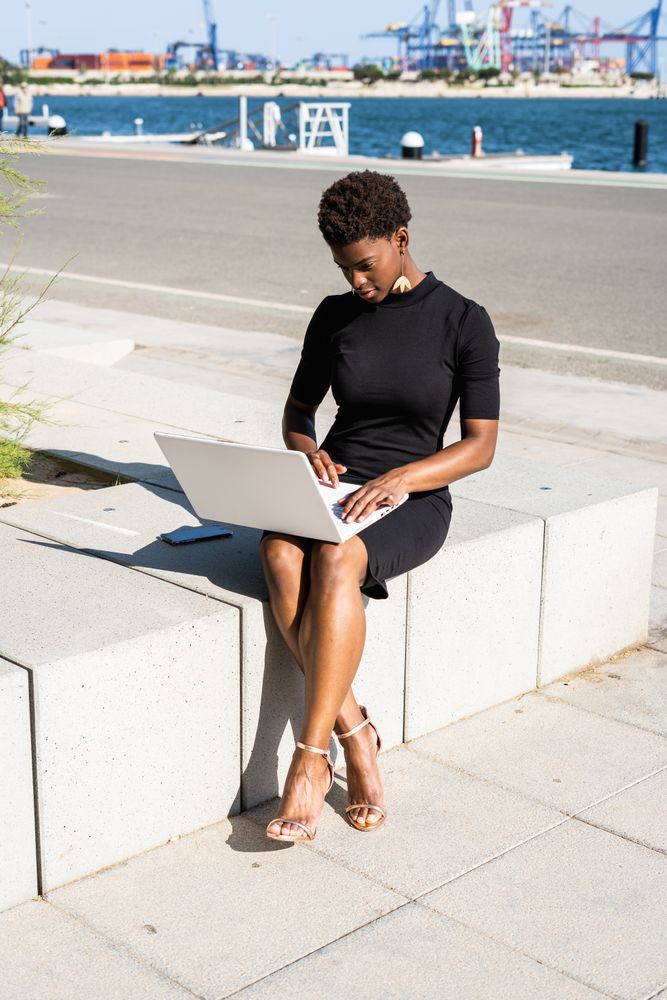 Serious female surfing laptop near modern building