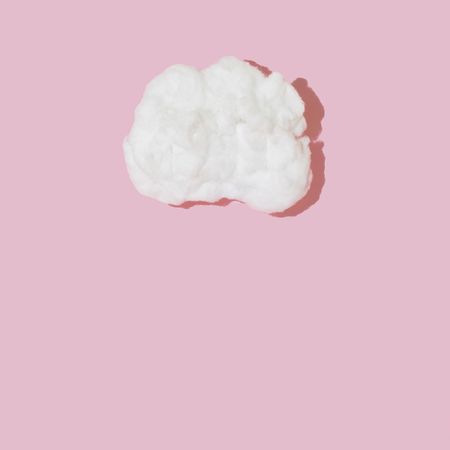 Single cotton cloud on pink background