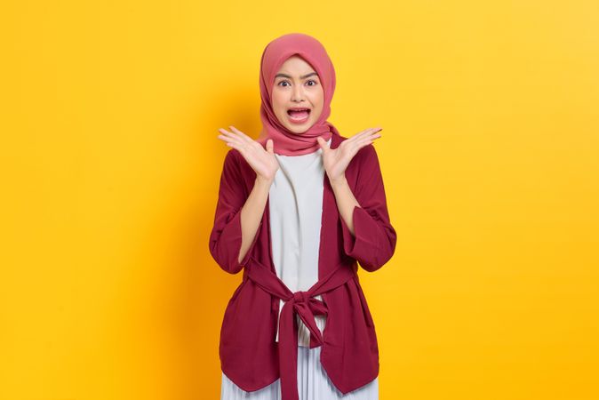 Disgusted woman in red headscarf with both hands up