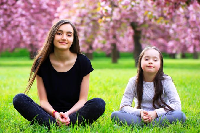 Portrait of two young siblings sitting in a park smiling