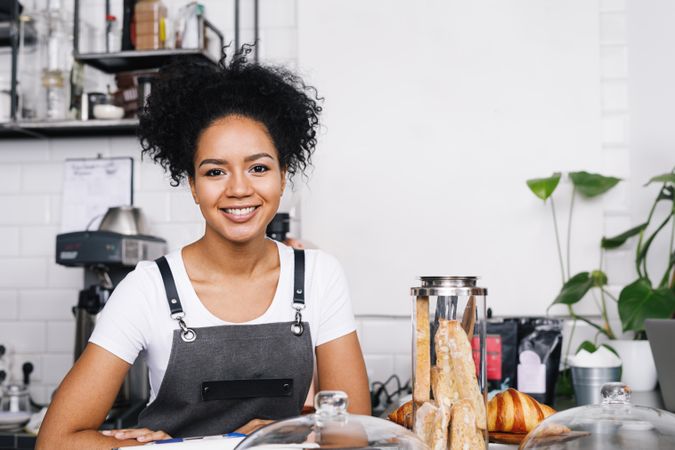 Happy barista in apron in her shop