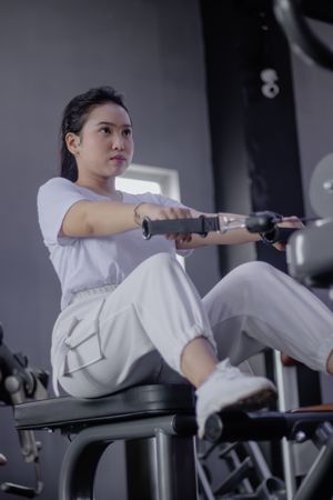 Dedicated woman exercising arms with seated cable rows machine