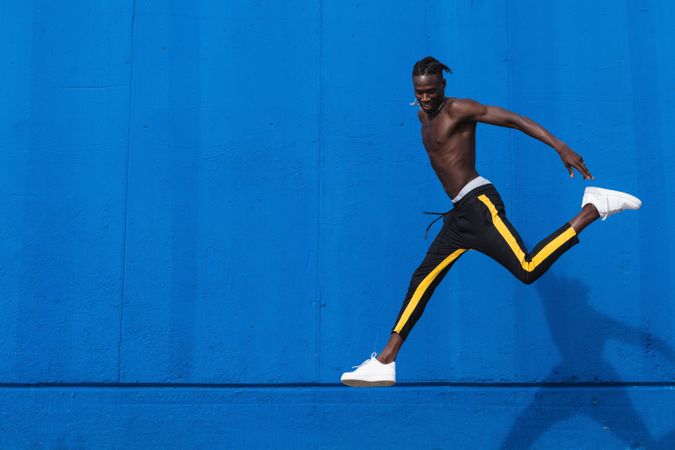 Cheerful Black man jumping on street
