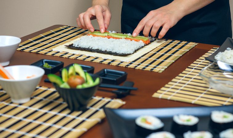 Chef placing avocado on rice as she makes fresh sushi rolls