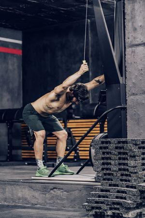 Athletic male pulling ropes in gym