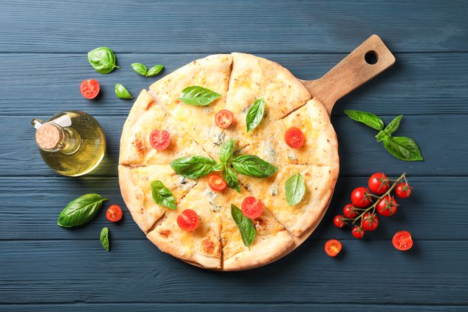 Cheese pizza, tomatoes and olive oil on wooden background, copy space